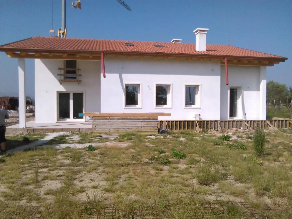 Facciata di una casa con tetto in coppi, finestre e portefinestre installate